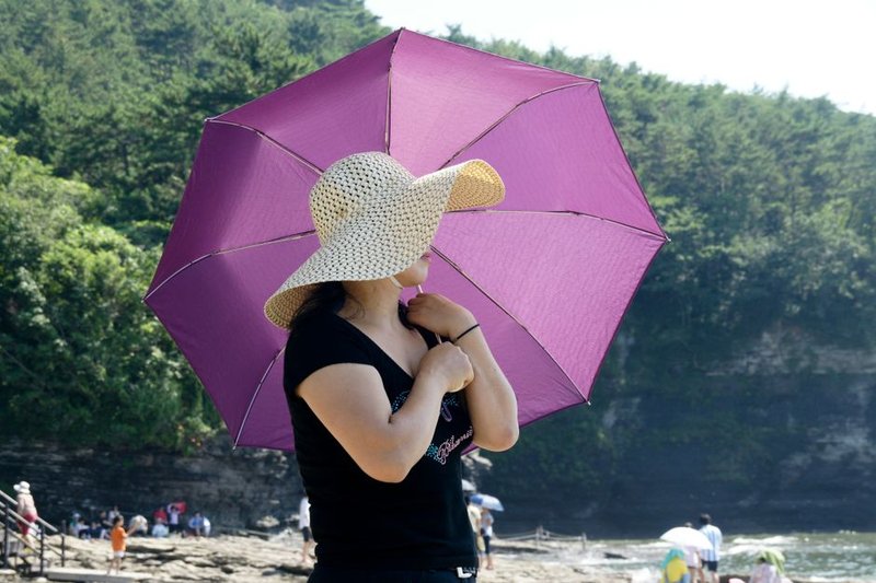 女士戴遮阳帽拿粉色遮阳伞走在阳光下